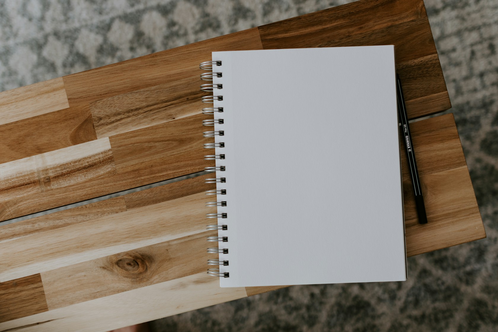 Cuaderno de espiral en blanco con bolígrafo sobre mesa de madera para planificar gastos