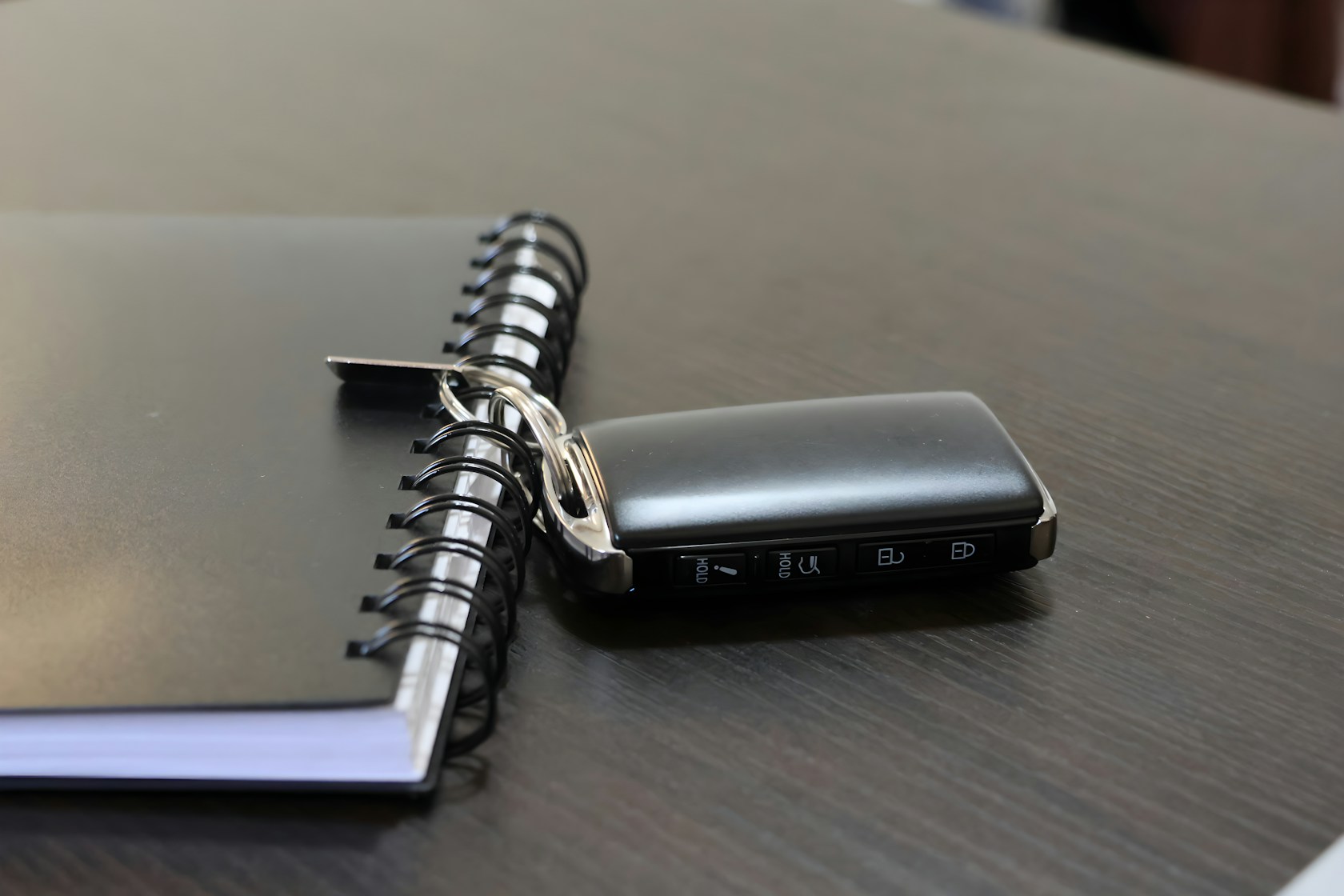 Llave de coche junto a un cuaderno azul sobre el escritorio al planificar la compra