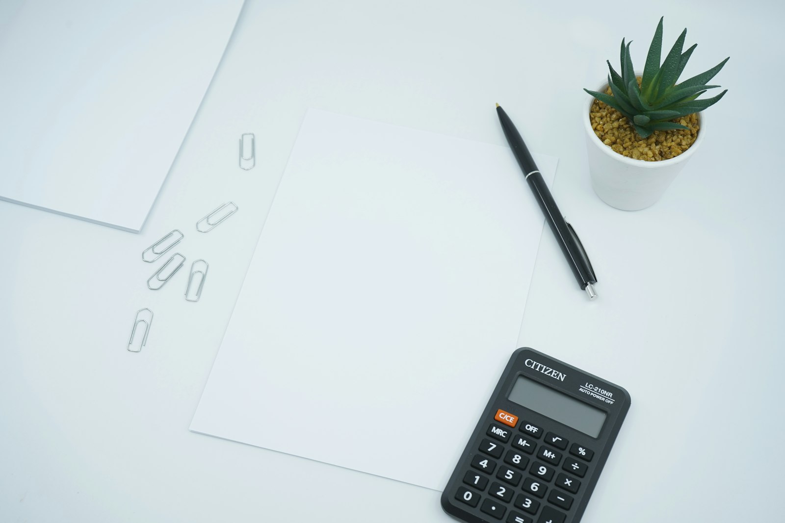 Calculadora y bolígrafo sobre un papel en blanco, simulando el cálculo de un préstamo de 50.000 euros