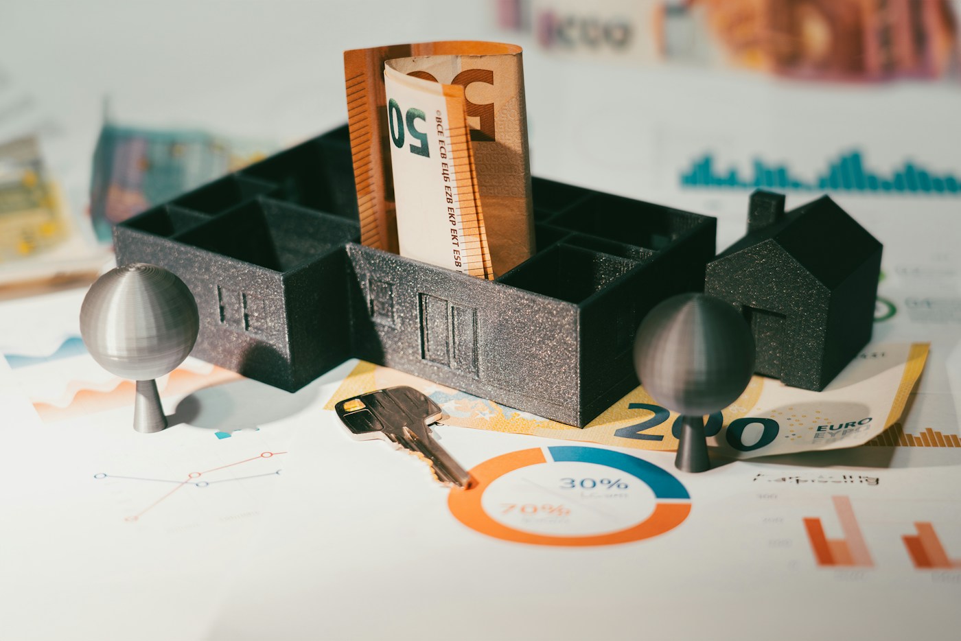 Préstamo con garantía hipotecaria: maqueta de vivienda, llaves y billetes sobre una mesa