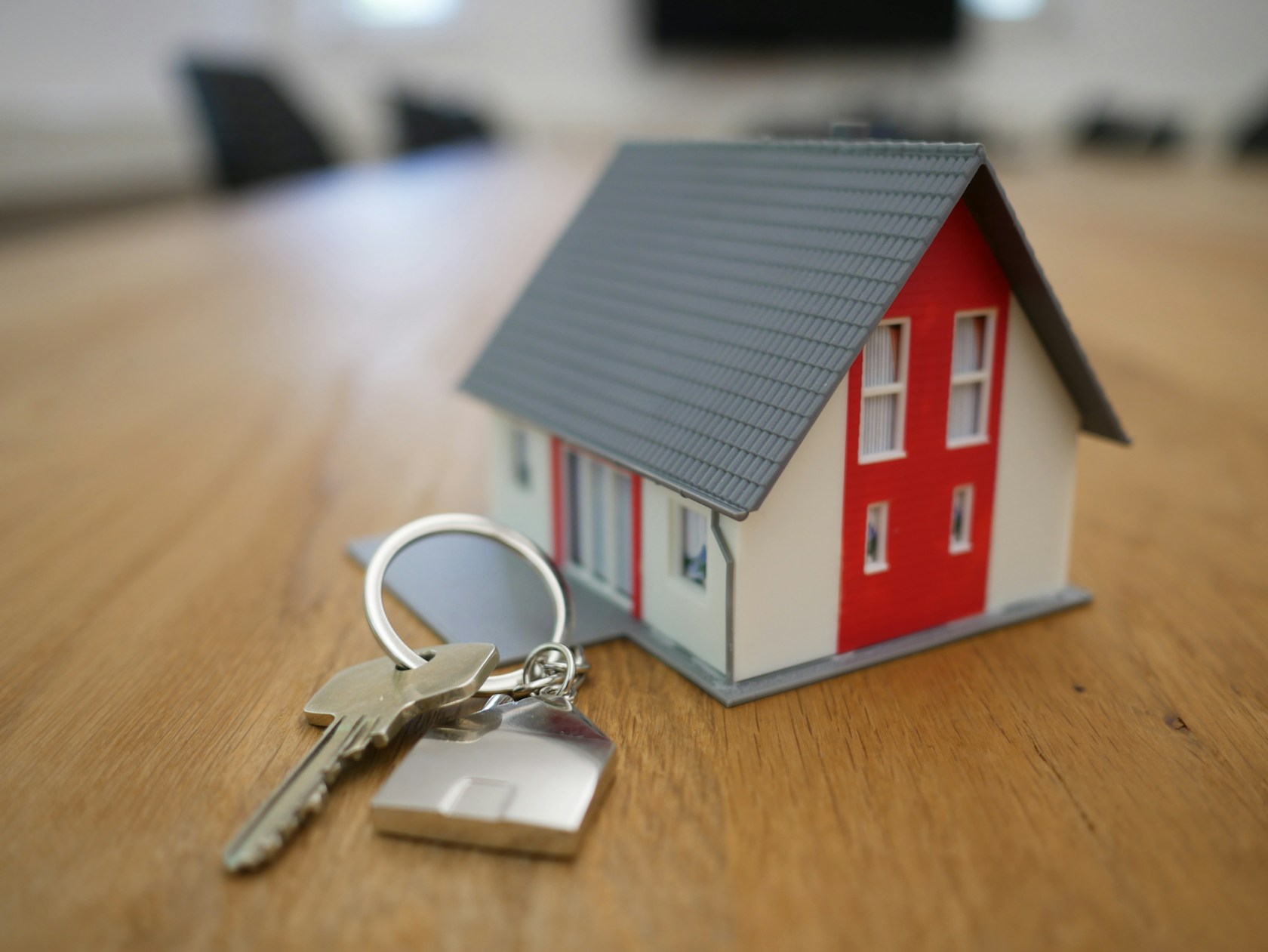 Llaves y maqueta de una casa sobre una mesa: préstamo sin nómina con propiedad como garantía