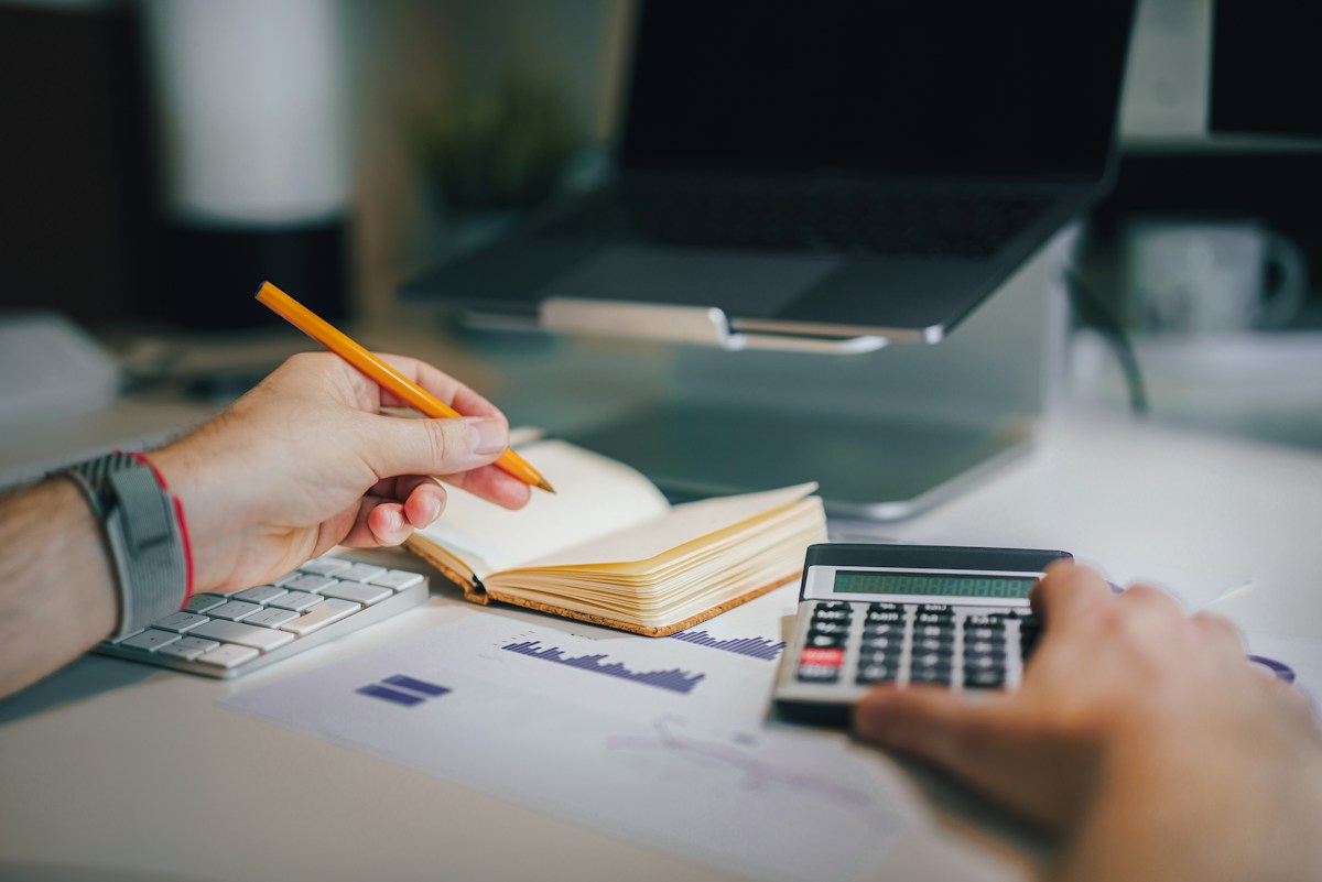 Persona revisando su presupuesto con calculadora y cuaderno antes de pedir un préstamo personal