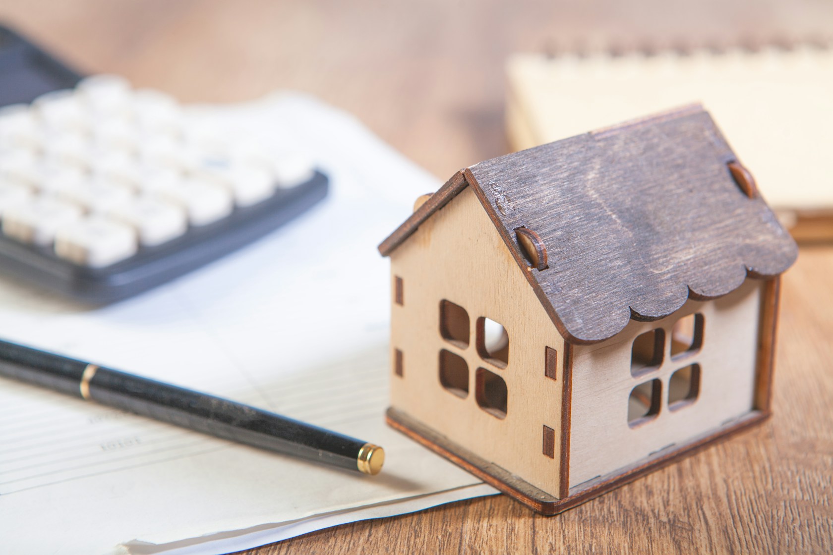 Valor de tasación de la vivienda: maqueta de casa junto a calculadora y documentos para calcular el préstamo